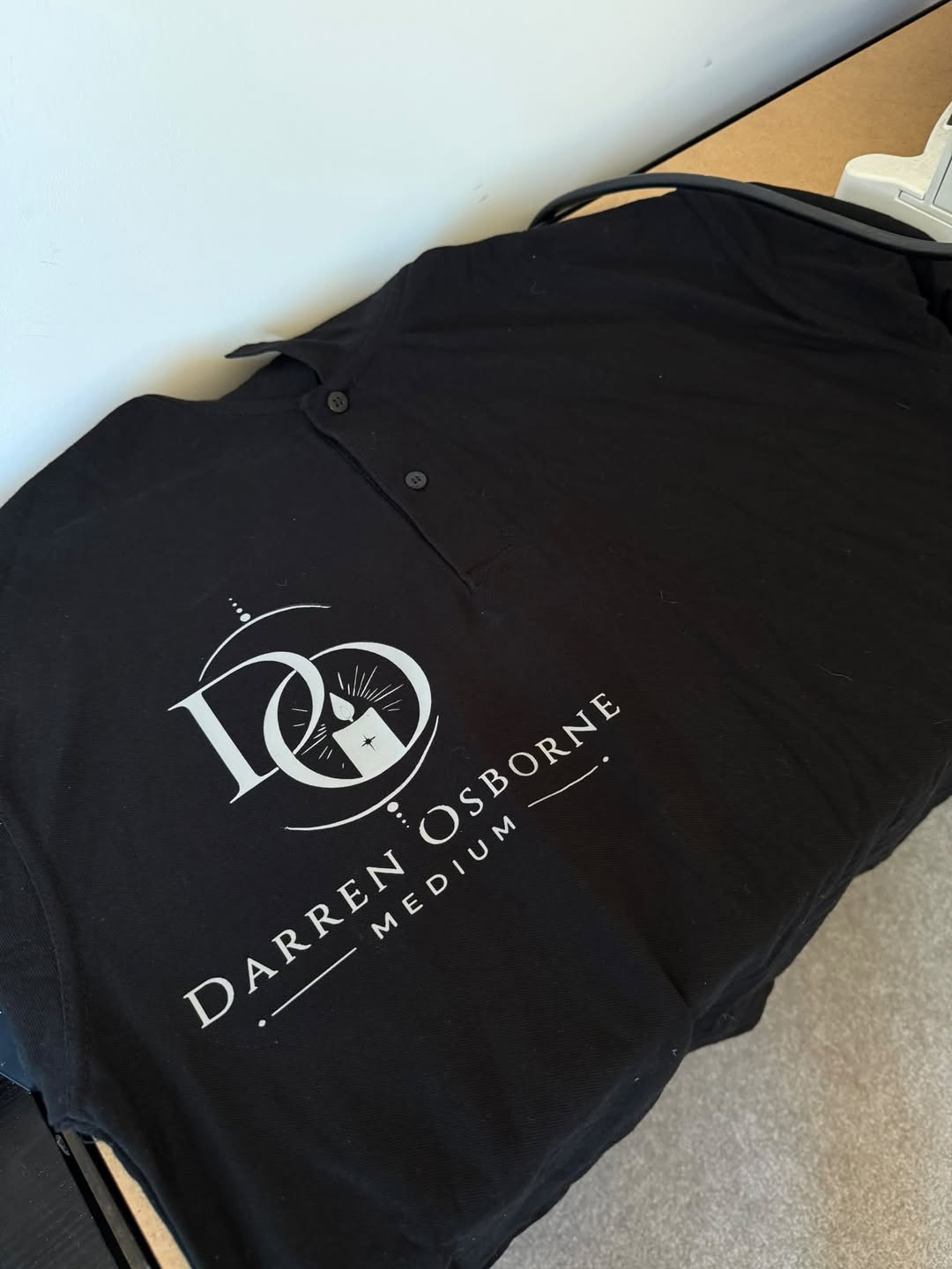 Darren Osborne Medium logo printed on a black polo shirt